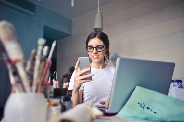 A young woman with glasses looks at her phone