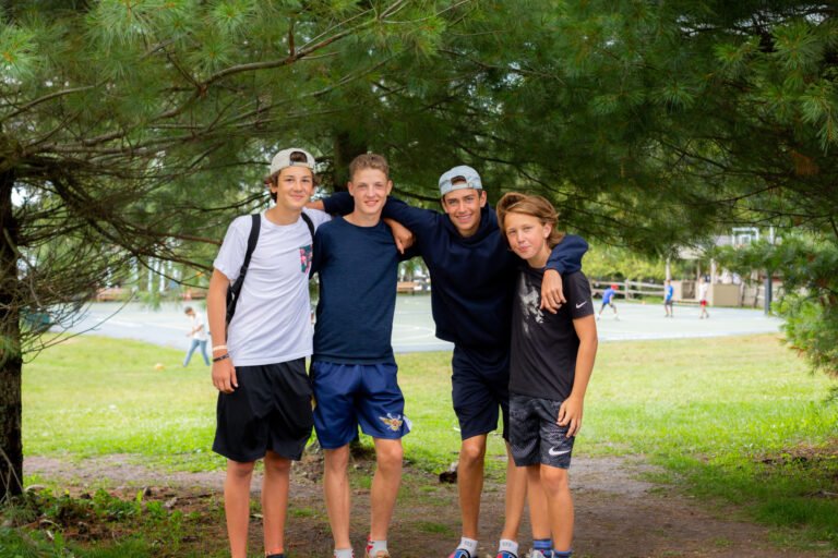Four boys posing for photo underneath a tree