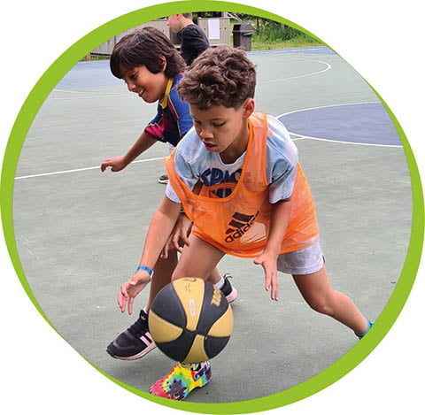 a boy in an orange pinny bounces a basketball