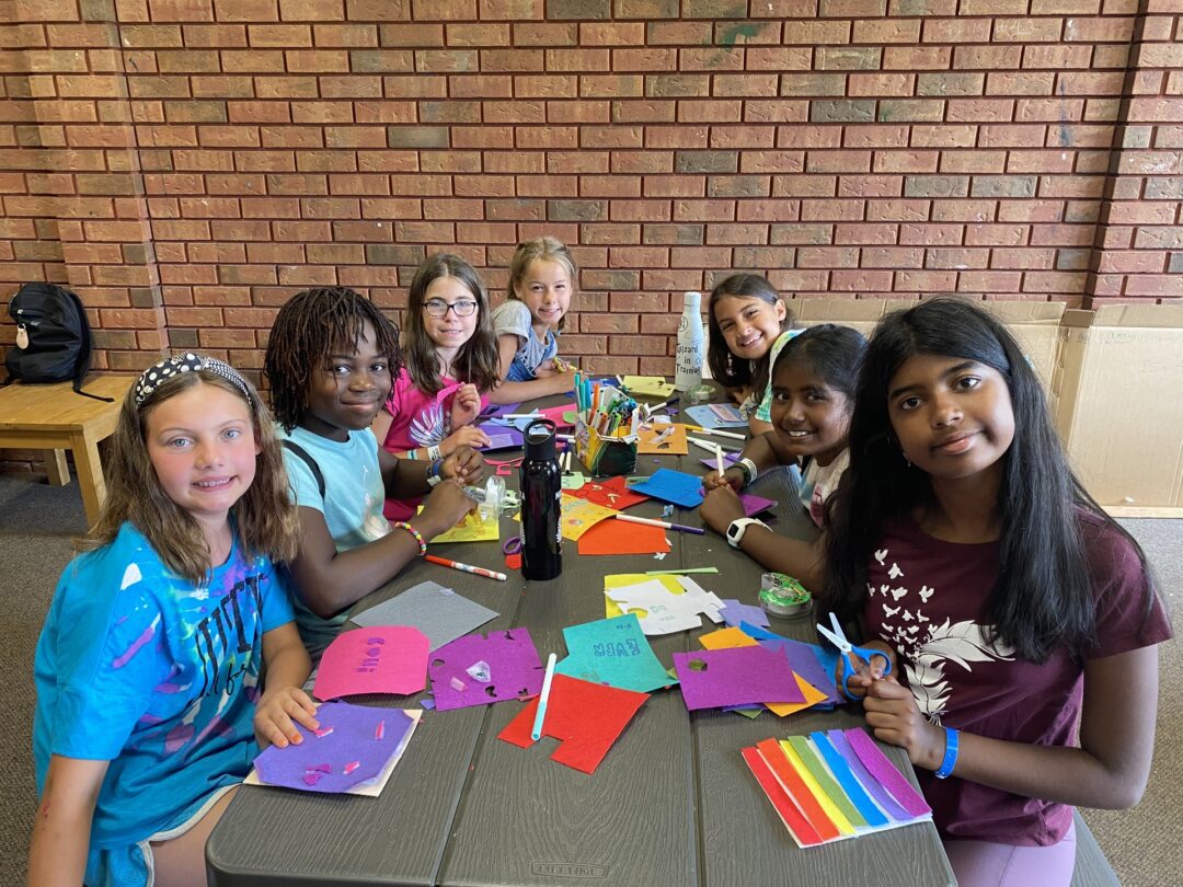 girls sitting at a table making crafts