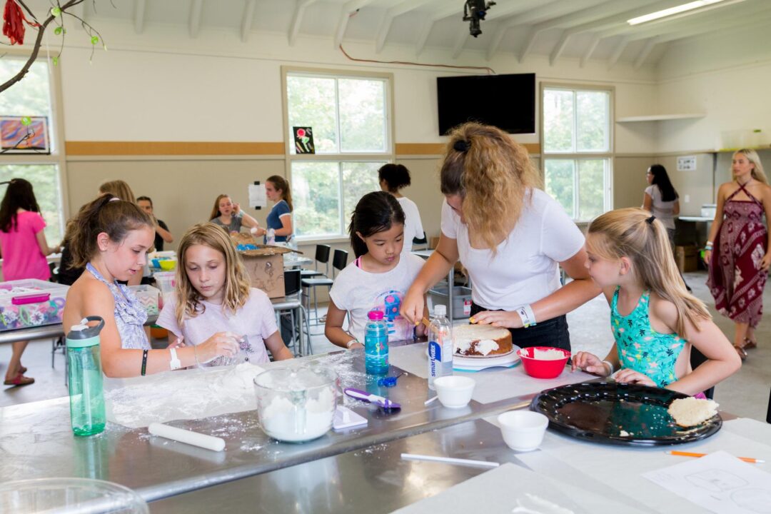 a group of girls decorating a cake
