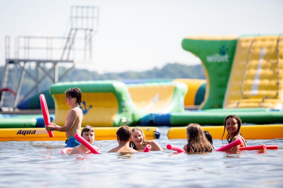 kids in the water with pool noodles