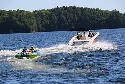 tubing on the water at Muskoka Woods A boat pulling kids on a tube in the water<br />